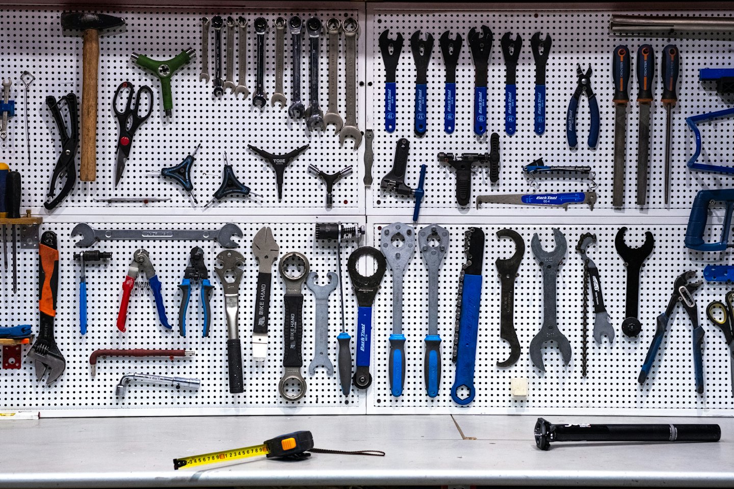 Un tablero de clavijas muestra una colección organizada de herramientas de reparación de bicicletas.